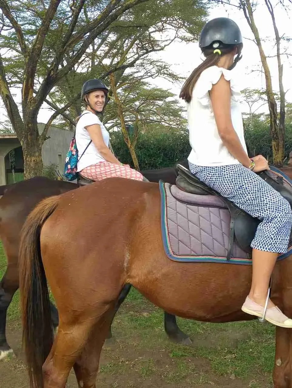 Mother and daughter horseback riding on a forest trail